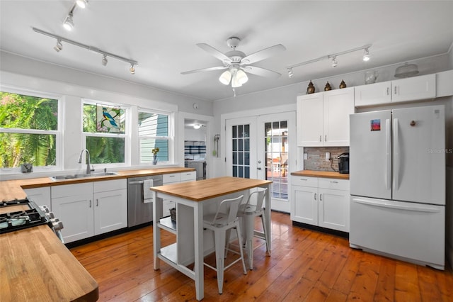 kitchen featuring wooden counters, sink, a wealth of natural light, rail lighting, and white fridge