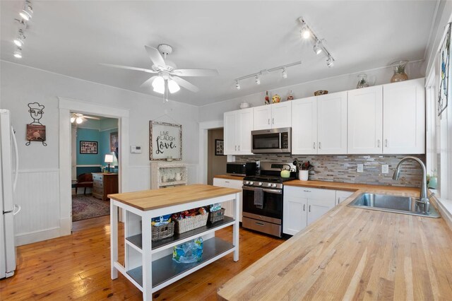 kitchen with tasteful backsplash, butcher block counters, ceiling fan, appliances with stainless steel finishes, and sink