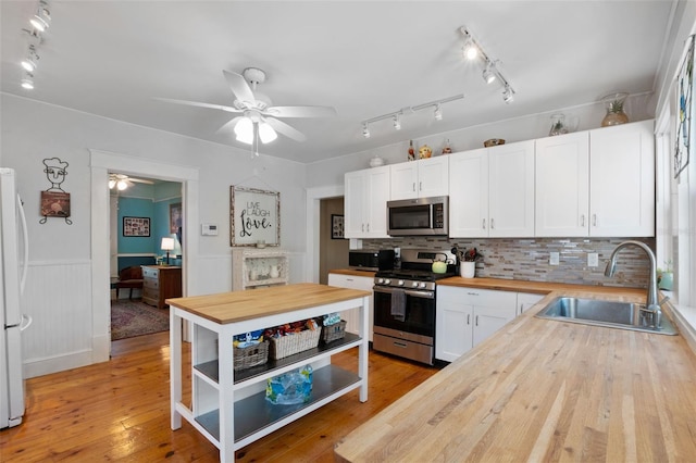 kitchen featuring butcher block counters, sink, white cabinets, stainless steel appliances, and light hardwood / wood-style flooring