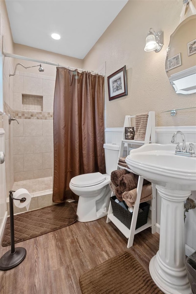 bathroom featuring wood-type flooring, sink, curtained shower, and toilet