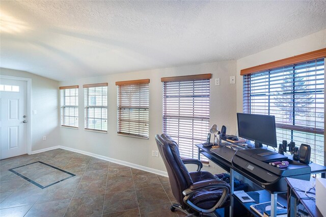 home office with dark tile patterned flooring, a textured ceiling, and a wealth of natural light