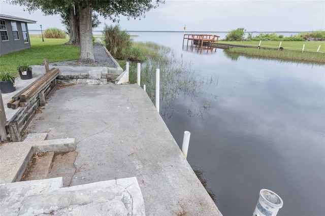 dock area with a water view and a lawn