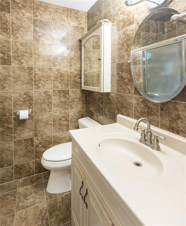 bathroom featuring vanity, toilet, and tile walls