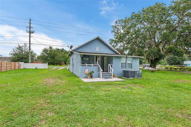 back of property featuring a yard, cooling unit, and covered porch