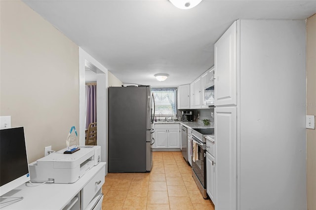 kitchen with sink, stainless steel appliances, light tile patterned floors, tasteful backsplash, and white cabinets