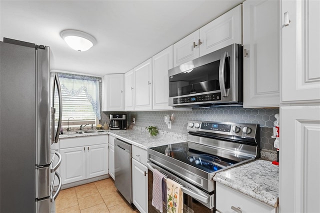 kitchen with sink, tasteful backsplash, light tile patterned floors, appliances with stainless steel finishes, and white cabinets