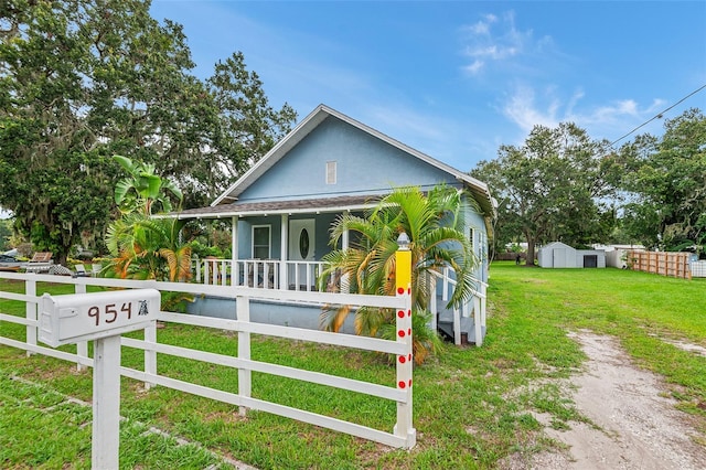 view of front of property with a porch, a front yard, and a shed