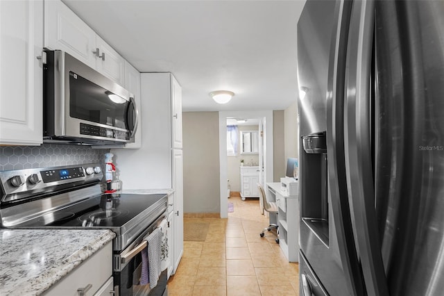 kitchen featuring white cabinetry, light stone counters, backsplash, light tile patterned floors, and appliances with stainless steel finishes