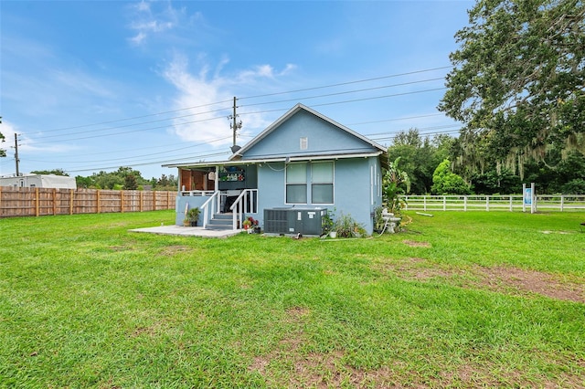 back of house featuring central AC unit and a lawn