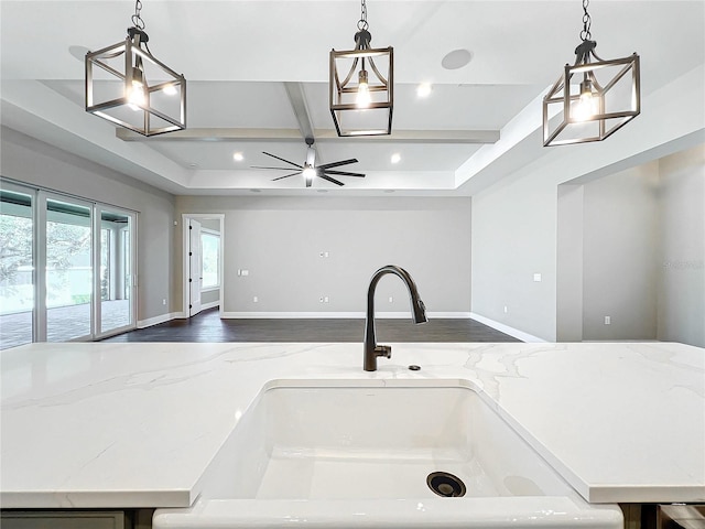 kitchen with light stone countertops, sink, wood-type flooring, and decorative light fixtures
