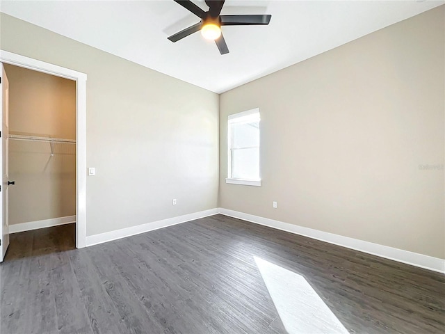 unfurnished bedroom with dark hardwood / wood-style flooring, a closet, a spacious closet, and ceiling fan