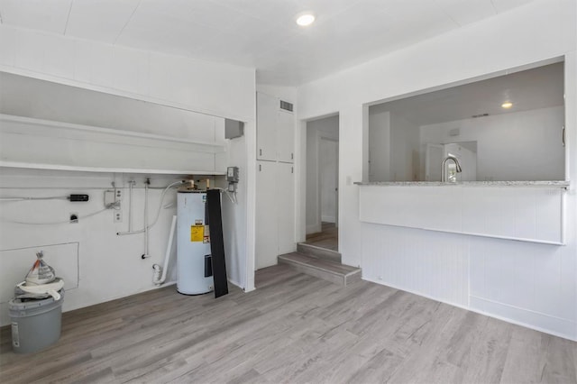 interior space with sink, light hardwood / wood-style flooring, electric water heater, and vaulted ceiling