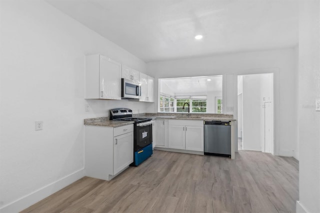 kitchen with white cabinetry, stainless steel appliances, sink, and light wood-type flooring