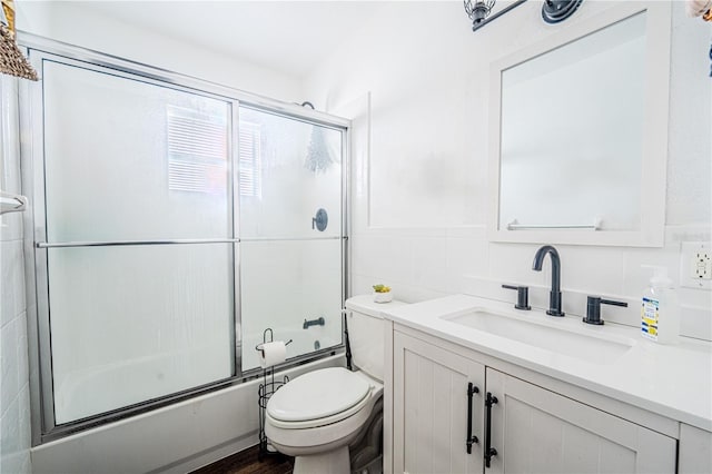 full bathroom featuring tile walls, toilet, enclosed tub / shower combo, and vanity