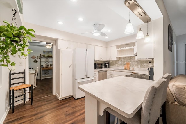 kitchen featuring dark hardwood / wood-style flooring, ceiling fan, stainless steel appliances, decorative backsplash, and pendant lighting