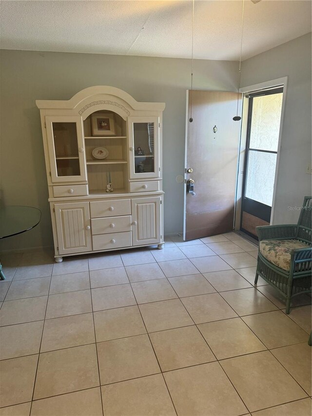 unfurnished dining area with light tile patterned flooring and a textured ceiling