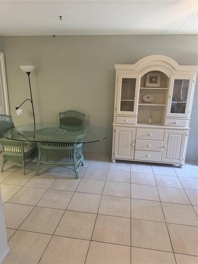 unfurnished dining area with a textured ceiling and light tile patterned flooring