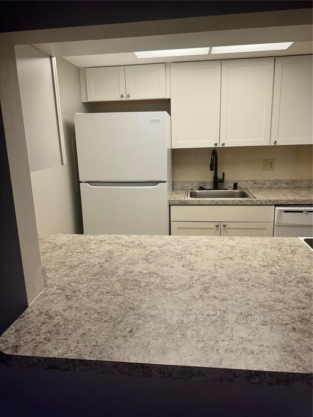 kitchen with sink, white appliances, and white cabinets