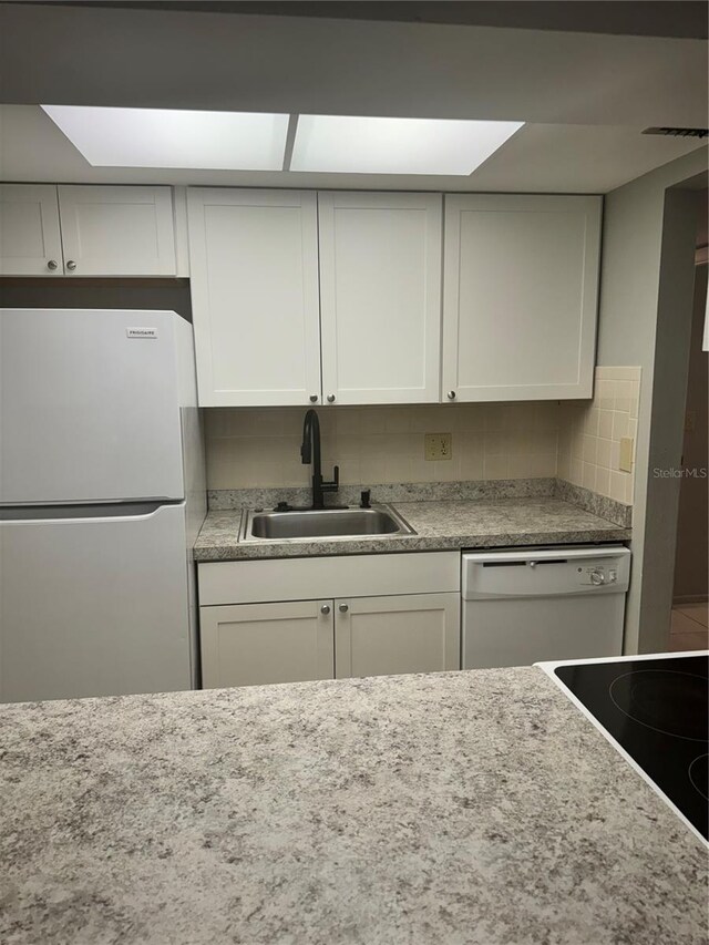 kitchen with refrigerator, sink, backsplash, white cabinets, and white dishwasher