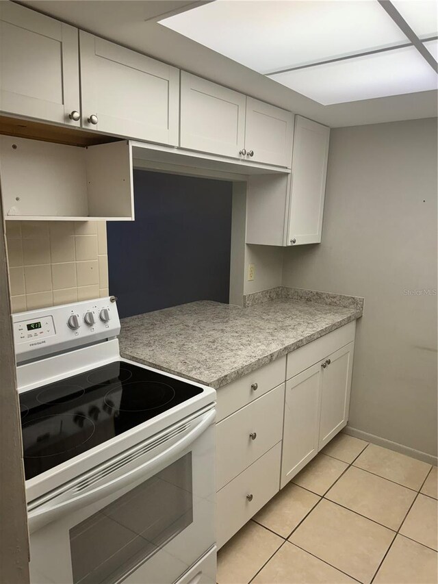 kitchen featuring white cabinetry, light tile patterned floors, decorative backsplash, and white range with electric stovetop