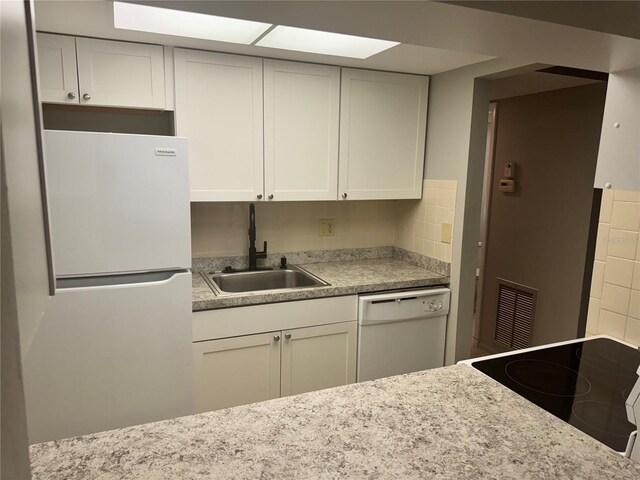 kitchen featuring sink, white appliances, white cabinets, and backsplash