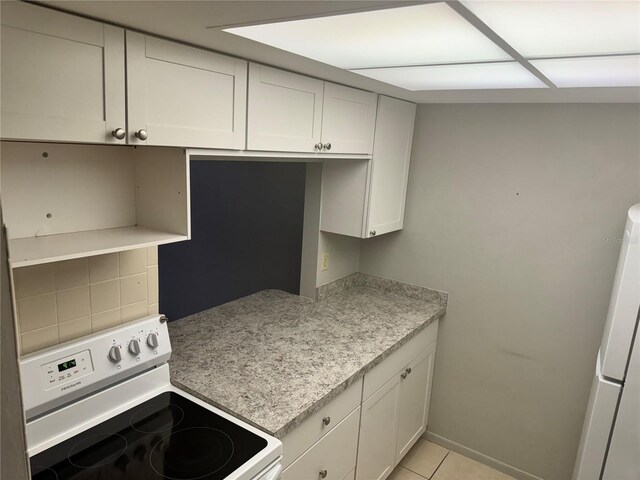 kitchen with light tile patterned floors, white appliances, white cabinetry, tasteful backsplash, and light stone counters