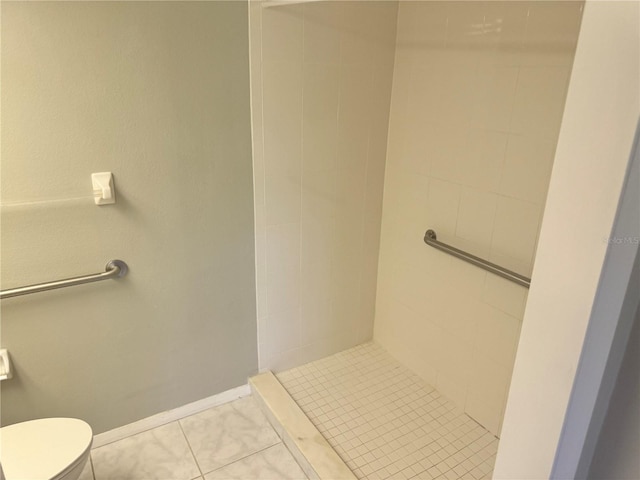 bathroom featuring toilet, tile patterned flooring, and a tile shower