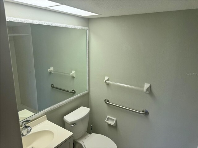 bathroom with vanity, a textured ceiling, and toilet