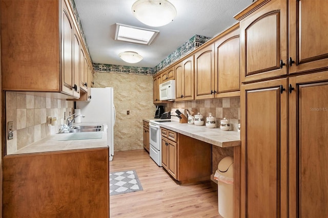 kitchen with white appliances, sink, a textured ceiling, tasteful backsplash, and light hardwood / wood-style floors