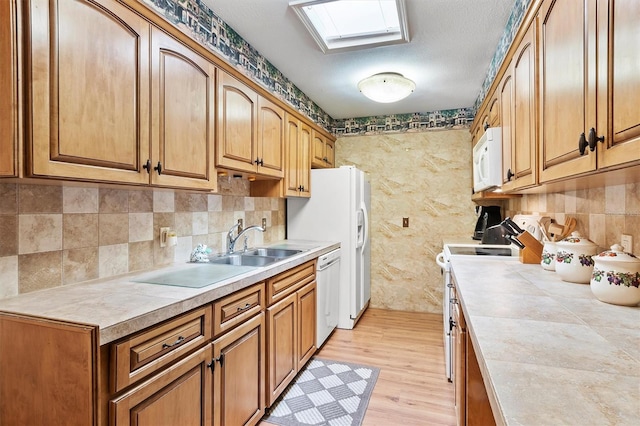 kitchen featuring decorative backsplash, light wood-type flooring, white appliances, and a textured ceiling