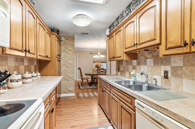 kitchen featuring hanging light fixtures, crown molding, a chandelier, light hardwood / wood-style floors, and white appliances