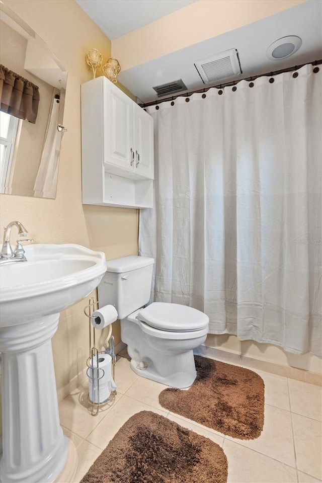 bathroom with toilet, tile patterned floors, and sink