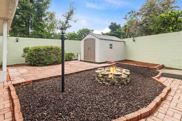 view of yard featuring a storage unit, an outdoor fire pit, and a patio area