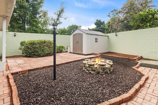 view of yard featuring a storage shed, a fire pit, a fenced backyard, an outbuilding, and a patio area