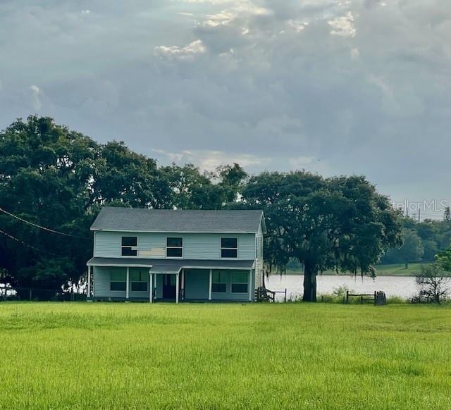 view of front of house with a front lawn and a water view