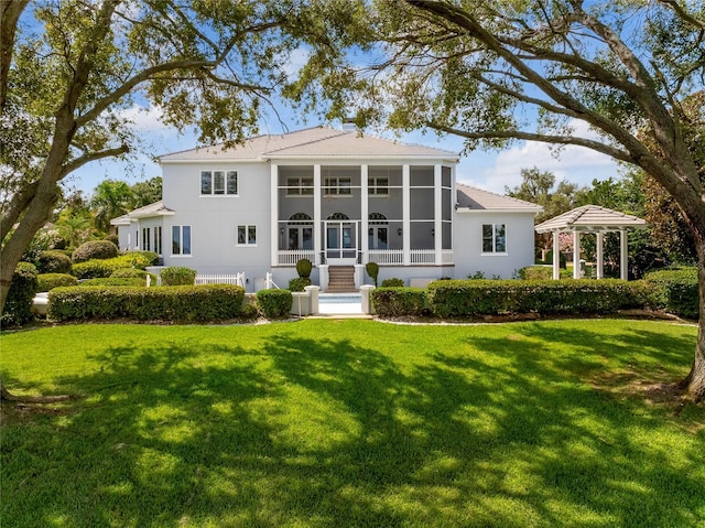 back of house featuring a sunroom and a lawn