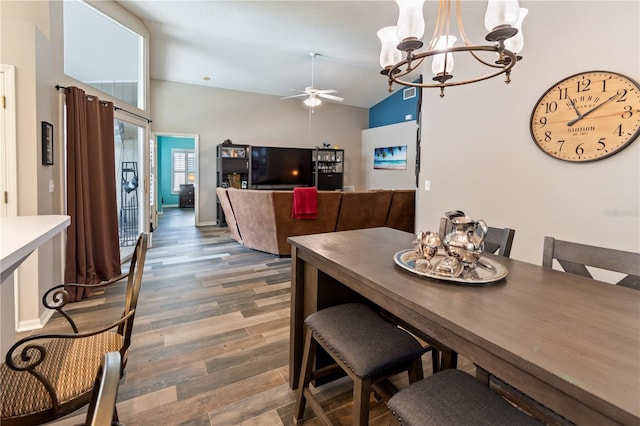 dining space with dark hardwood / wood-style flooring, ceiling fan with notable chandelier, and vaulted ceiling