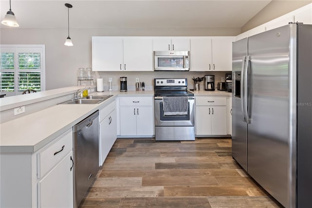 kitchen featuring white cabinetry, sink, stainless steel appliances, vaulted ceiling, and decorative light fixtures