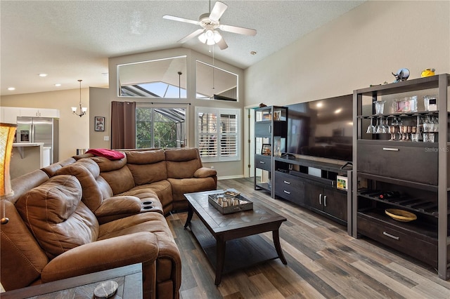 living room featuring a textured ceiling, ceiling fan with notable chandelier, hardwood / wood-style flooring, and lofted ceiling