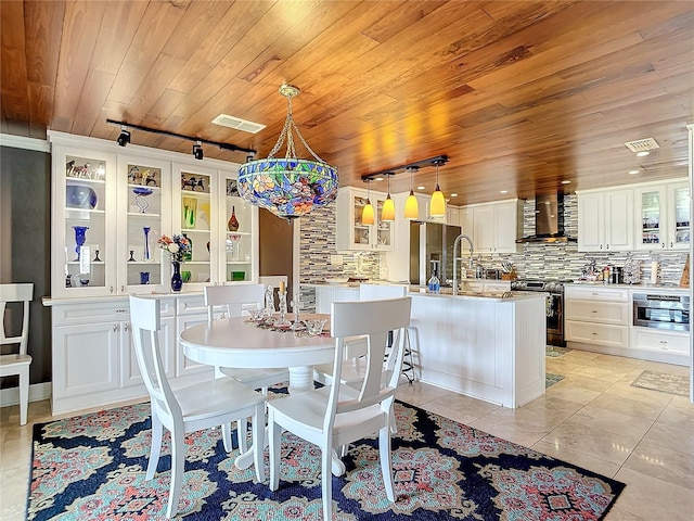 dining room featuring rail lighting, sink, light tile patterned flooring, and wood ceiling
