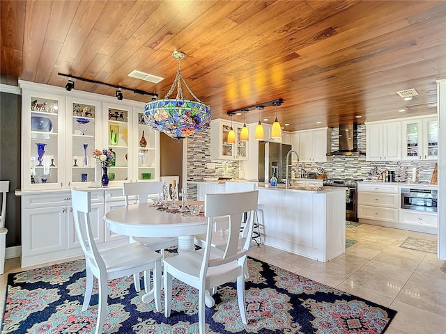 tiled dining space with track lighting and wood ceiling