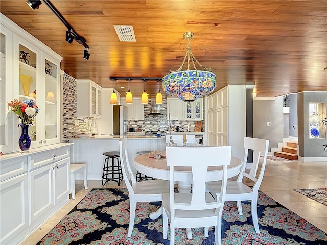 dining space with light tile patterned floors, track lighting, and wooden ceiling