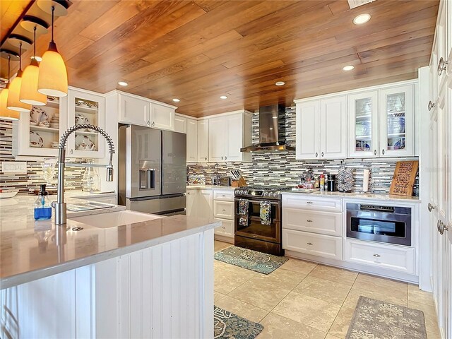 kitchen with white cabinetry, stainless steel appliances, light stone counters, wall chimney exhaust hood, and pendant lighting