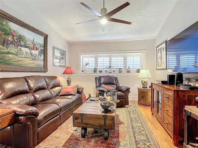 living room with light hardwood / wood-style floors, vaulted ceiling, ceiling fan, and a textured ceiling