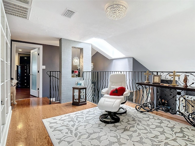 living area with an inviting chandelier, wood-type flooring, and lofted ceiling