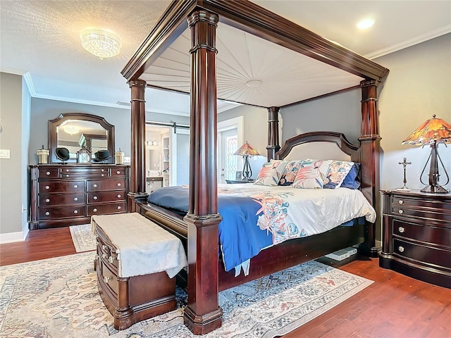 bedroom with ornate columns, crown molding, wood-type flooring, and a textured ceiling