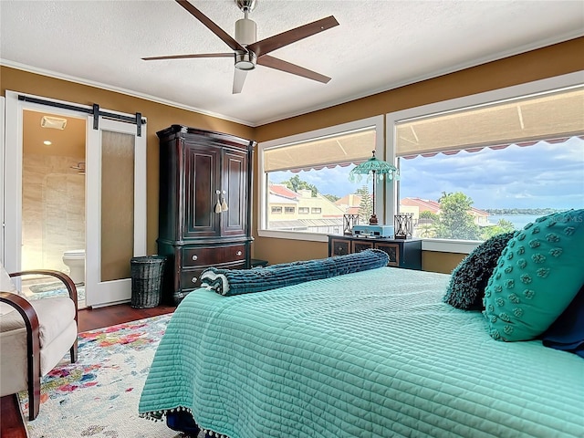 bedroom with dark wood-type flooring, a textured ceiling, ceiling fan, ensuite bathroom, and a barn door