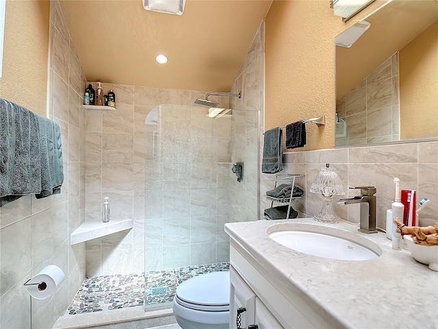 bathroom featuring tile walls, toilet, vanity, and a tile shower