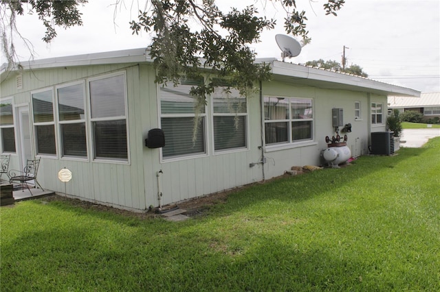 view of side of home with central AC and a lawn