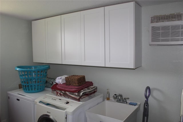 laundry room featuring a wall unit AC, sink, cabinets, and separate washer and dryer